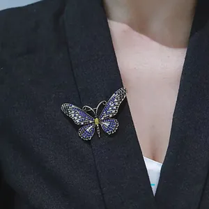 Squisita spilla a farfalla con cristalli blu e bianchi su un blazer nero da donna