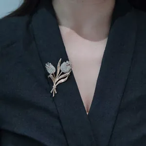 Elegante spilla a tulipano dorata con cristalli bianchi su una giacca scura da uomo