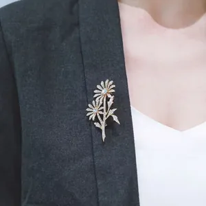 Elegante spilla doppia margherita dorata con cristalli appuntata sul bavero di un blazer grigio