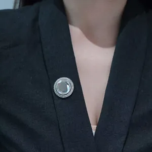 Elegant silver brooch with clear crystal center and pavé rhinestones on black blazer