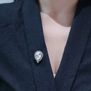 Elegant pear-shaped pearl and rhinestone brooch pinned on a dark blue suit lapel