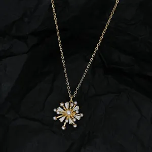 Détail du pendentif flocon doré avec perles et cristaux sur tissu noir plissé
