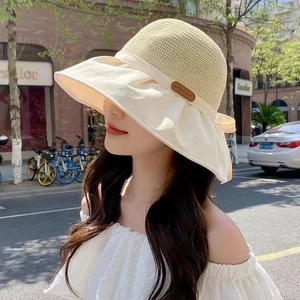 Detail of summer sun hat featuring straw weave crown and wide ruffled fabric brim