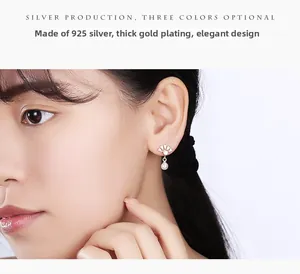 Détail de boucles d'oreilles éventail en argent 925 plaqué or avec perle blanche
