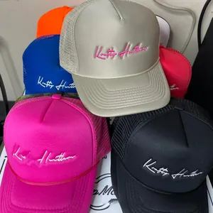 Detail showing various colors of trucker hats with custom 3D script embroidery