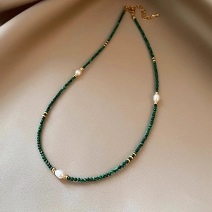 Malachite and freshwater pearl necklace with gold accents on a silk background
