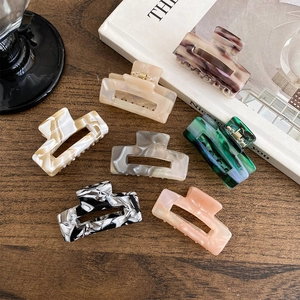 Rectangular acetate hair claws in various marble textures on a wooden background