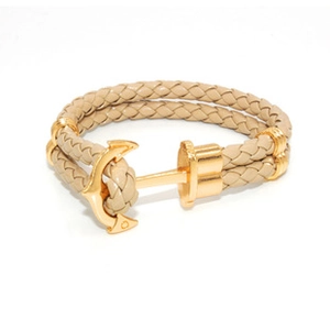 Detail of light brown braided leather bracelet with golden anchor clasp on white background