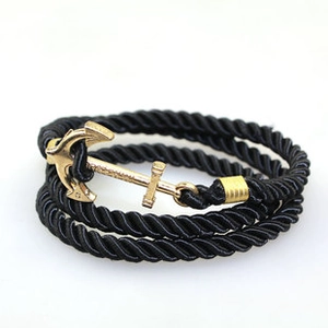 Macro shot of nautical multi-layer black braided rope bracelet with gold anchor clasp
