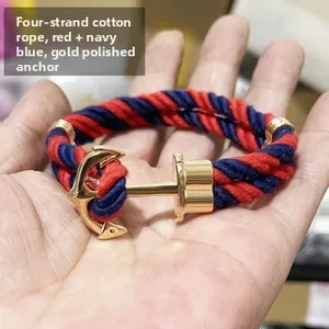 Detail of red and navy blue braided cotton rope bracelet with gold anchor hook