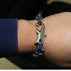 Close-up of a blue braided anchor rope bracelet with a dolphin shaped metal clasp