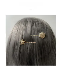 Détail de barrettes dorées en forme d'étoile de mer et de coquillage sur cheveux gris