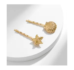Détail des barrettes dorées en alliage avec motifs de coquillage et étoile de mer