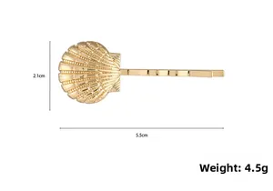 Détail d'une barrette coquillage dorée avec dimensions 5,5 cm et 2,1 cm sur blanc