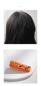 Detail of orange resin hair clip with colorful rhinestones on a white display base
