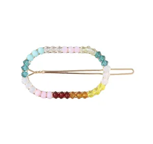 Macro detail of oval gold hair clip featuring colorful multifaceted handmade beads