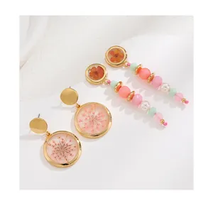 Detail view of resin earrings with dried flowers and colorful beads for women