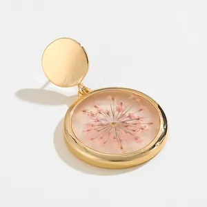 Golden resin earrings with pink dried flowers and smooth metallic round stud design