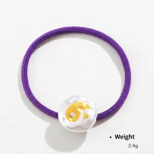 Elastic purple hair tie featuring a white textured bead with golden Yin Yang pattern