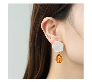 Gros plan sur les boucles d'oreilles fleur en nacre et pendentif en cristal ambré