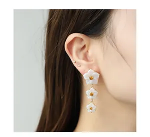 Boucles d'oreilles trois fleurs en résine blanche avec ambre sur un mannequin