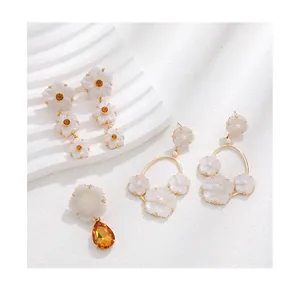 Vue détaillée de boucles d'oreilles florales avec pétales en résine ivoire et ambre