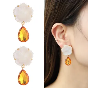 Boucles d'oreilles fleur en résine et cristal orange sur modèle et fond blanc