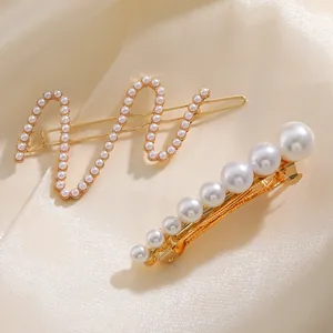Close-up of wavy gold hairpins with elegant pearls on luxury champagne silk fabric