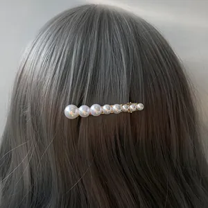 Elegant gold metal hair clip with graduated white pearls on smooth brown hair