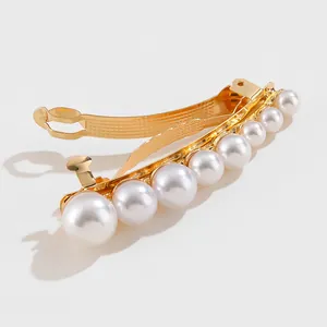 Detailed view of large-to-small gradient pearls on a gold-toned metal hair clip