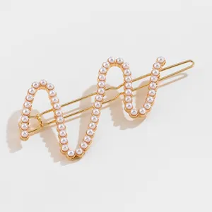 Detailed view of elegant wavy golden alloy hair clip with rows of small white pearls