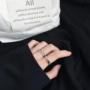 Detailed close-up of a silver twist ring featuring a black cross and chain connection
