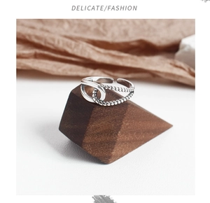 Macro detail of S925 sterling silver twisted rope ring on a minimalist wooden stand