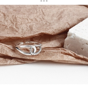 Macro shot of an adjustable vintage silver twisted rope ring on a textured background