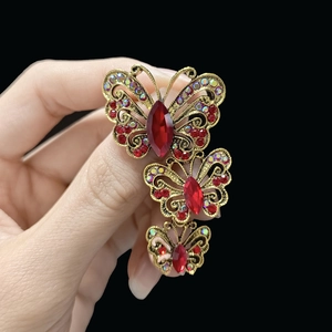Detailed view of triple butterfly brooch with red crystals and golden finish details