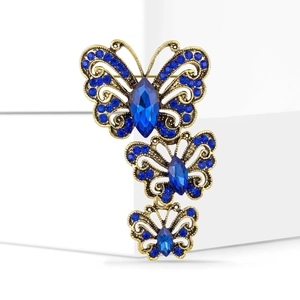 Detailed view of triple blue butterfly brooch with rhinestones on a golden base