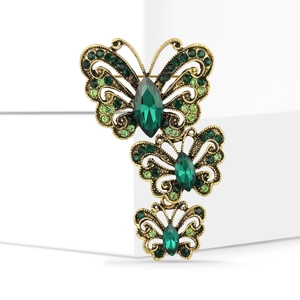 Macro detail of vintage butterfly brooch with green rhinestones and antique gold finish