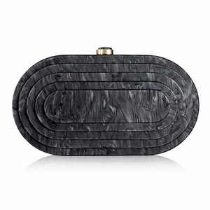 Detail of dark grey marble pattern acrylic clutch bag with golden metal clasp closure