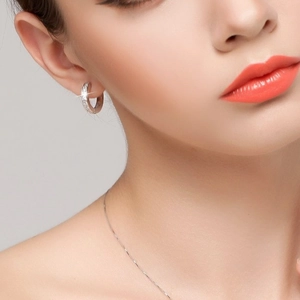Close-up of silver hoop earrings with micro-pave zircons worn by a female model