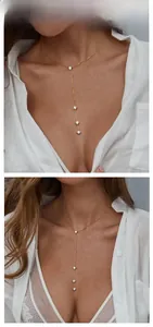 Macro detail of a golden Y-shaped tassel necklace featuring four round cubic zirconia stones