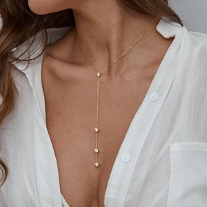 Elegant gold Y-shaped fringe necklace with sparkling white zircons on a female model