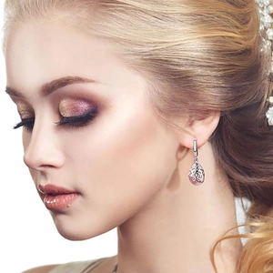 Vintage silver hollow-out teardrop earrings featuring pink crystal gemstones on female model