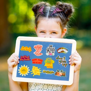 Close-up of colorful motivational stickers on a wooden board held by a child outdoors