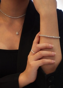 On-model view of silver tennis bracelet, necklace, and teardrop pendant jewelry set