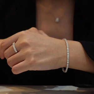 Close-up detail of luxury silver tennis bracelet, ring and pendant set with round crystals