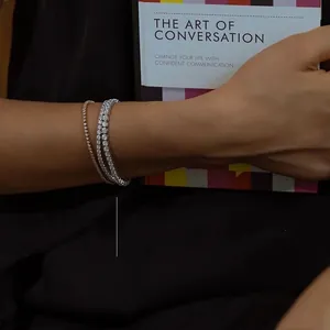 Detail of layered gold and silver tennis bracelets with sparkling stones on a model