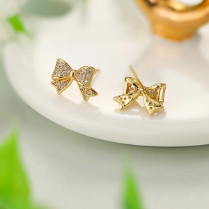 Detailed close-up of golden bow-shaped stud earrings with sparkling pave zircon stones