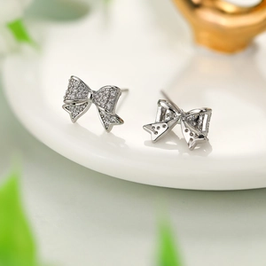 Macro shot of silver bow stud earrings with sparkling pavé cubic zirconia on a ceramic tray