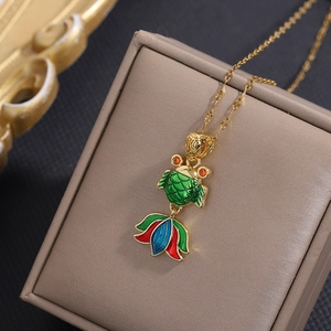 Macro detail of golden koi fish pendant with green enamel scales and lotus tail design