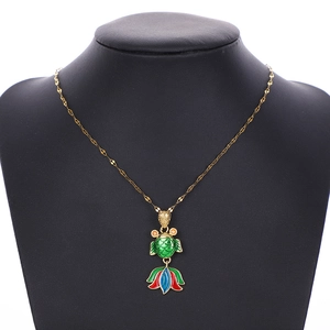 Detail of a vintage fish pendant with green enamel scales and decorative orange gems
